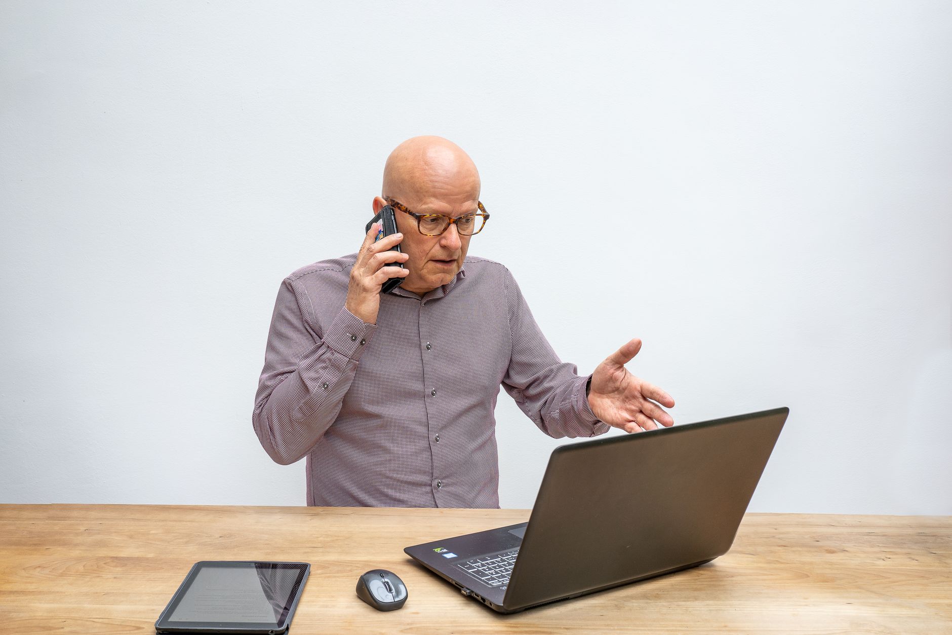 Older adult holding a smartphone next to a tablet showing a Bluetooth pairing screen