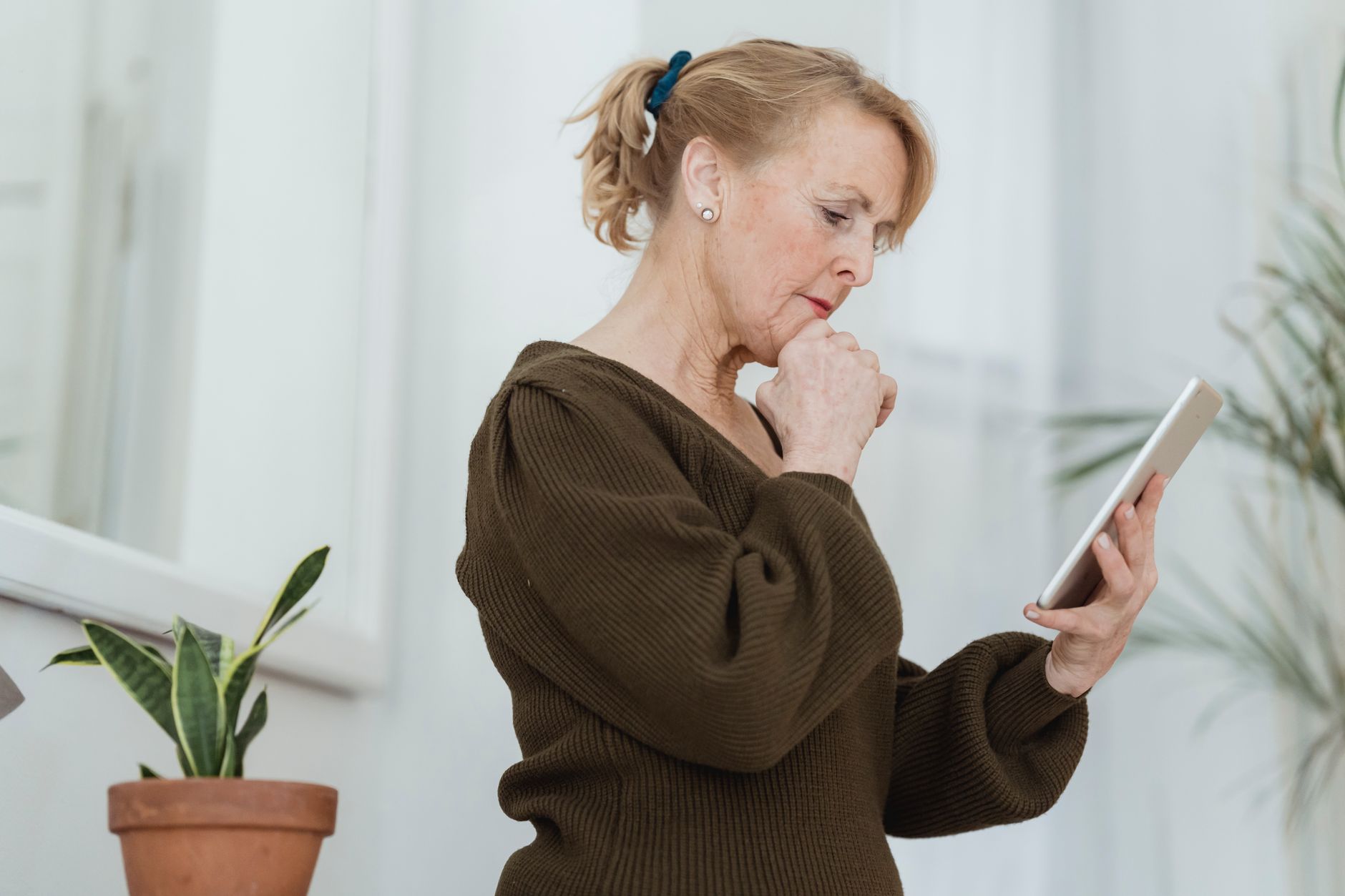 a senior woman reads an email on a tablet with a concerned look