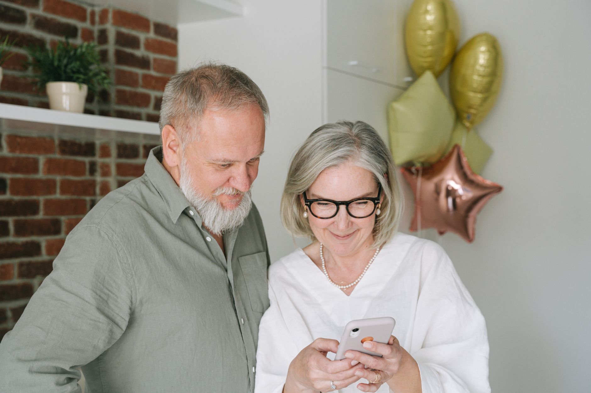 An older adult holding an iPhone with the Silence Unknown Callers setting visible on the screen.