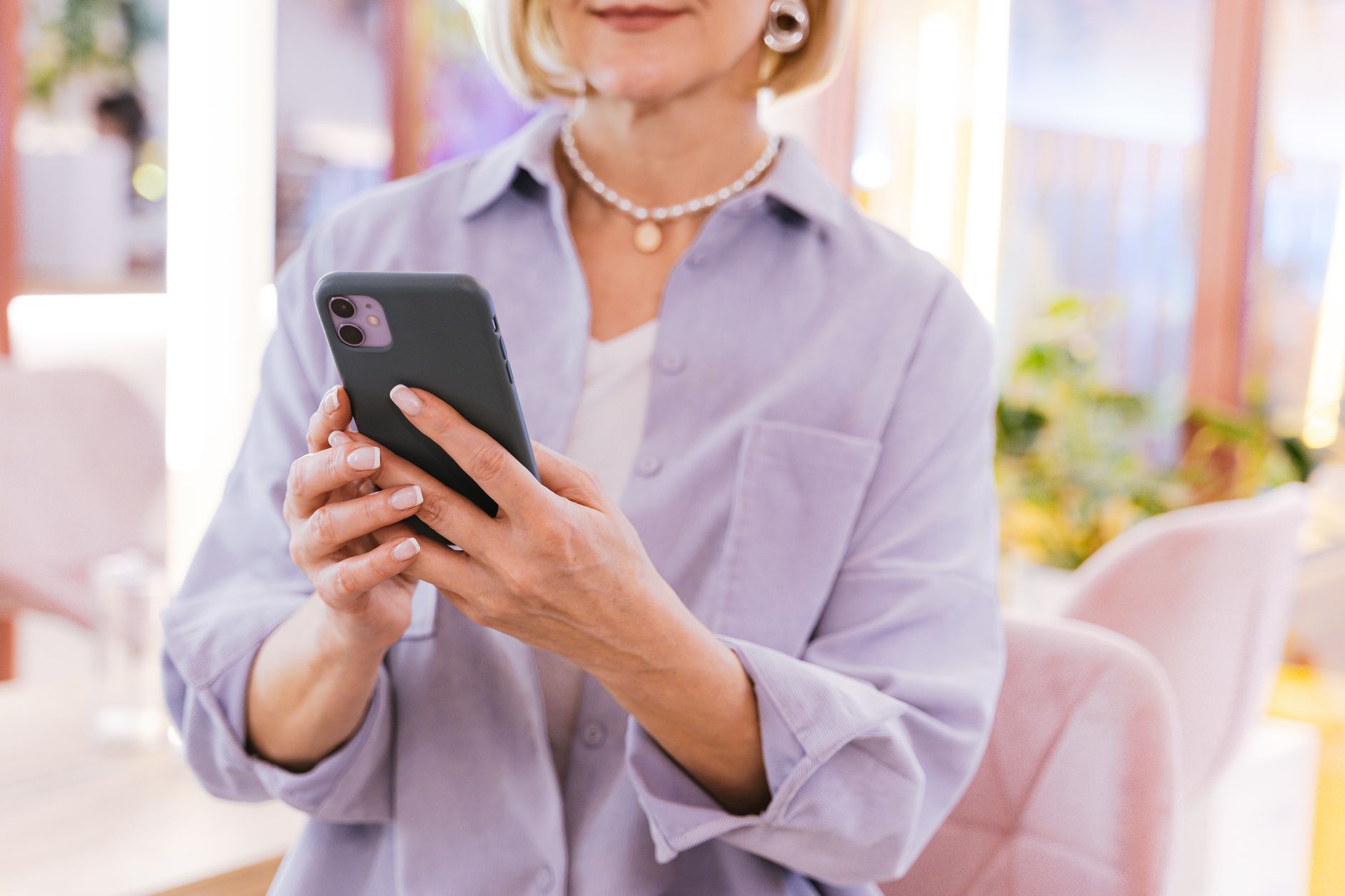 A senior woman holding an iPhone and adjusting the text size slider in the Accessibility settings.