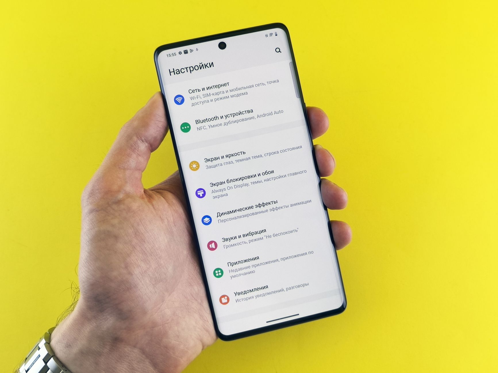 A person holding an Android phone and dragging the font size slider in the Settings app to the right.