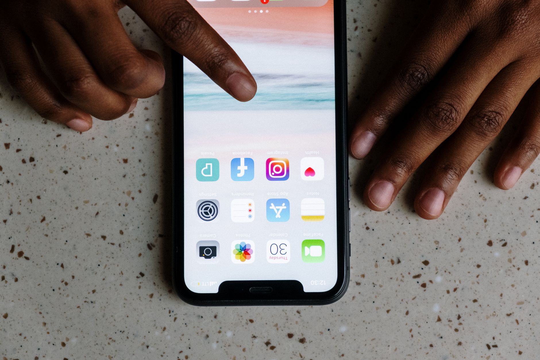 a senior woman tapping the Settings icon on an iPhone screen