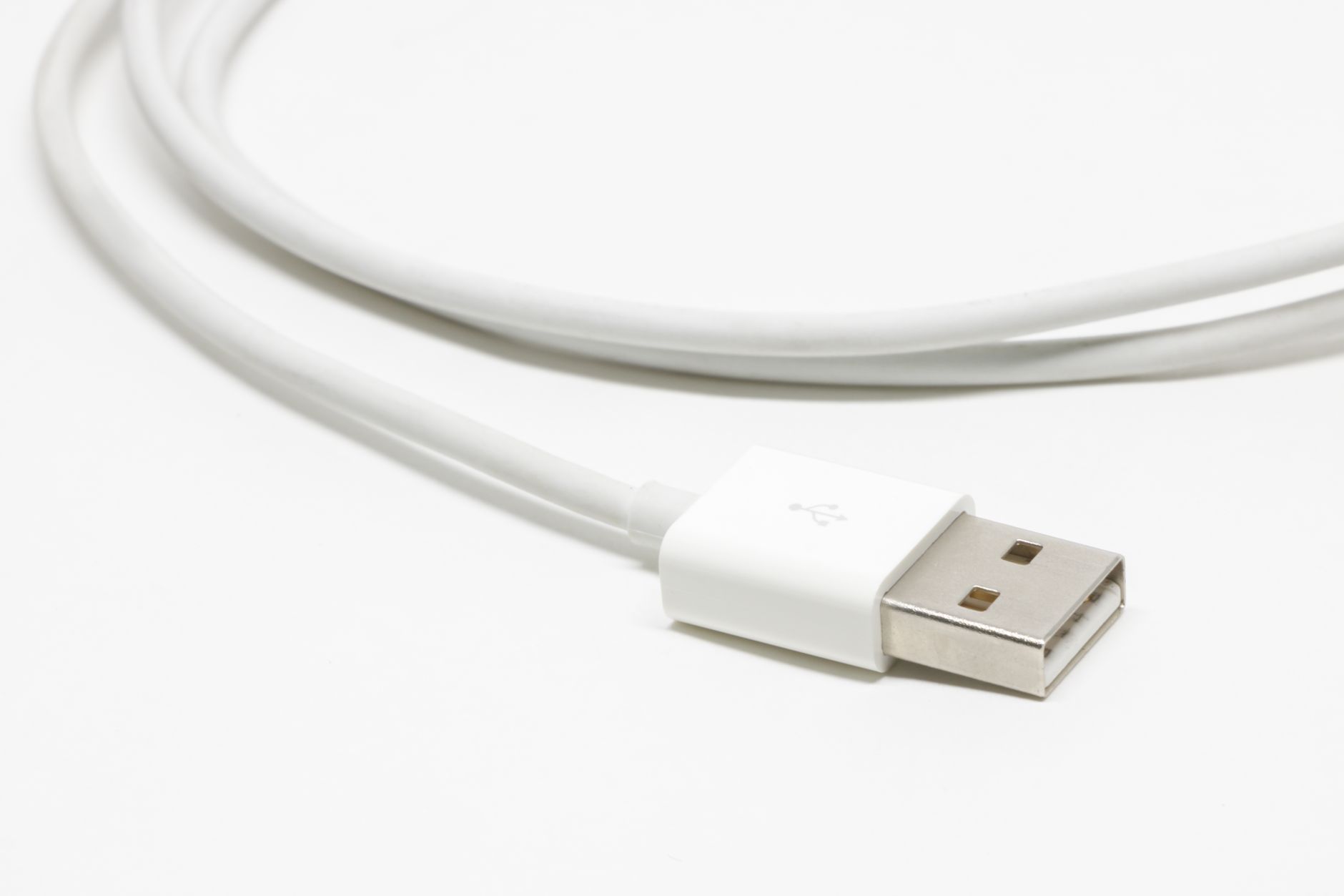 an older adult plugging an iPhone into a charging cable on a wooden table