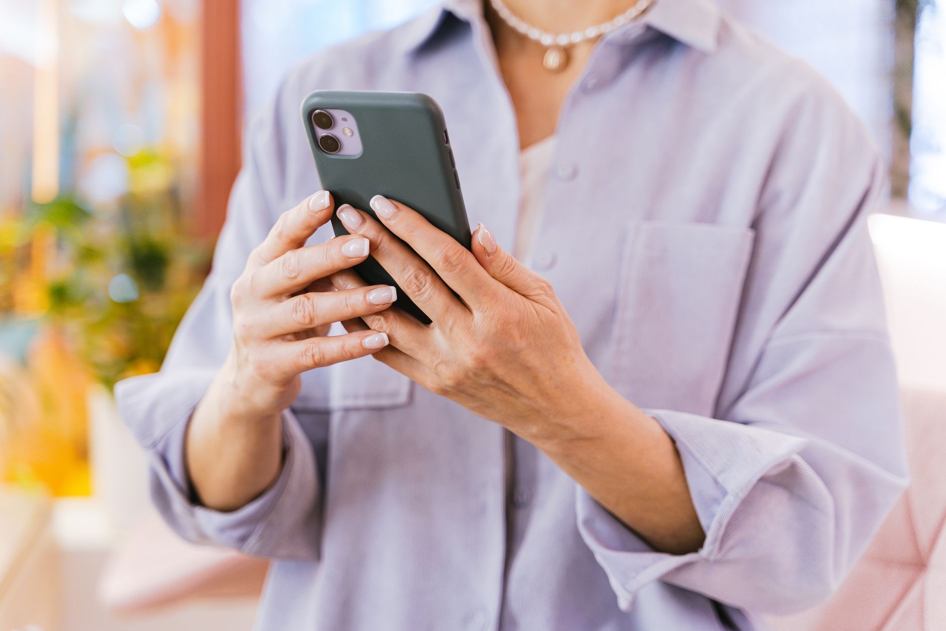 an older adult pressing the side button on an iPhone that shows the Hello screen