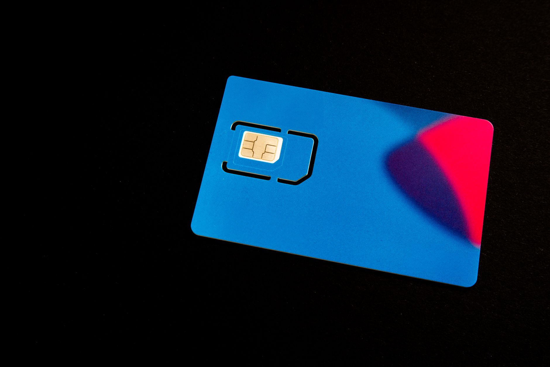 a hand inserting a SIM card into a smartphone tray on a wooden table