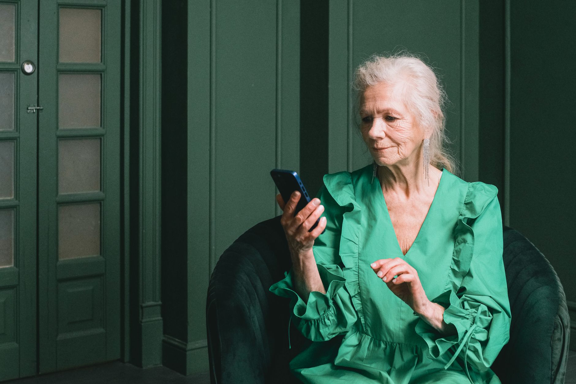 a senior smiling while looking at a smartphone displaying the Google Photos app