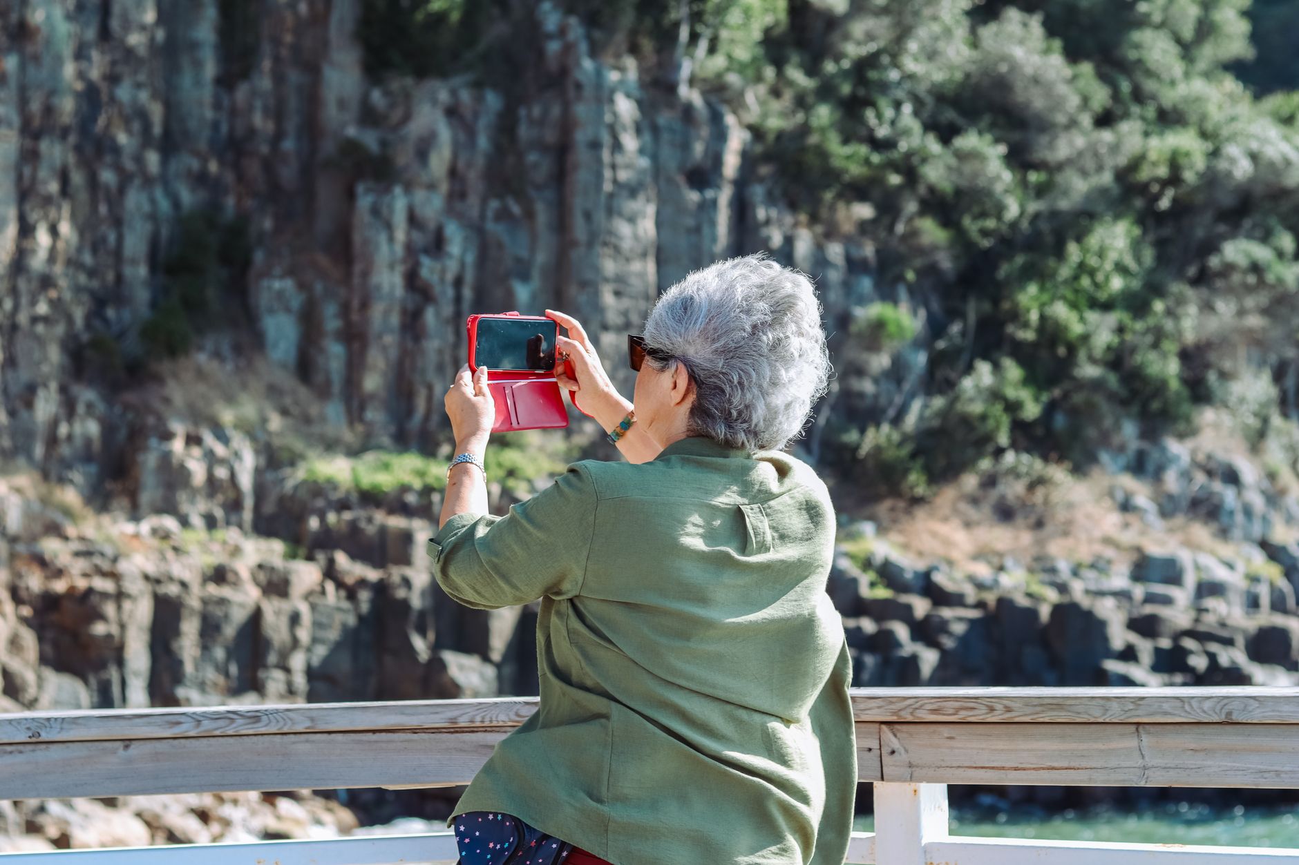 an older adult using a tablet camera to photograph flowers
