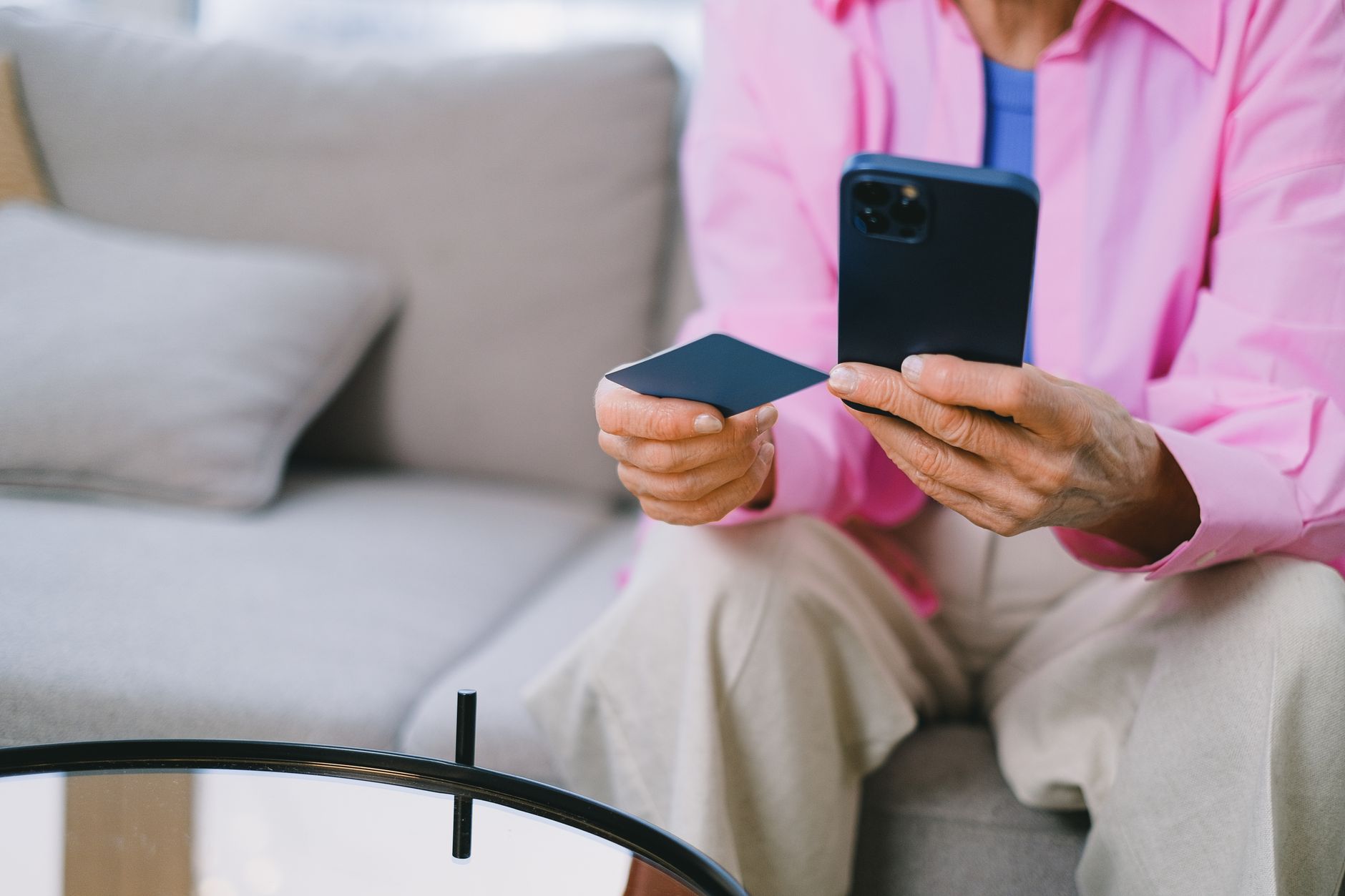 a senior woman using a mobile banking app on a smartphone while sitting at a kitchen table