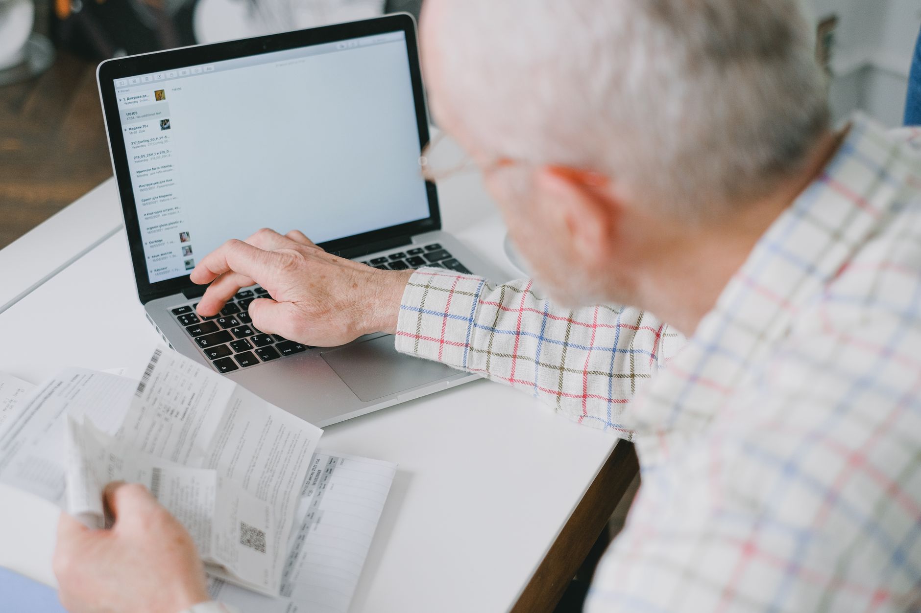 a senior man reviewing a bank statement on a laptop at a clean desk