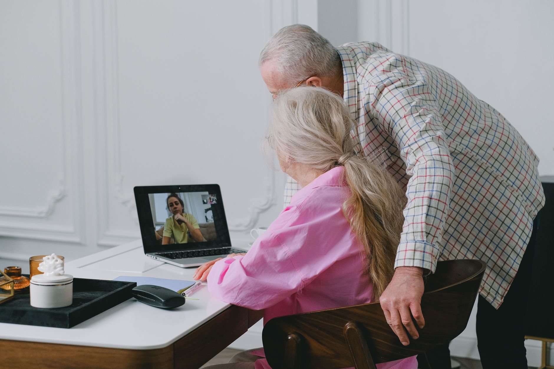 a senior using a laptop with a video call app download page on the screen