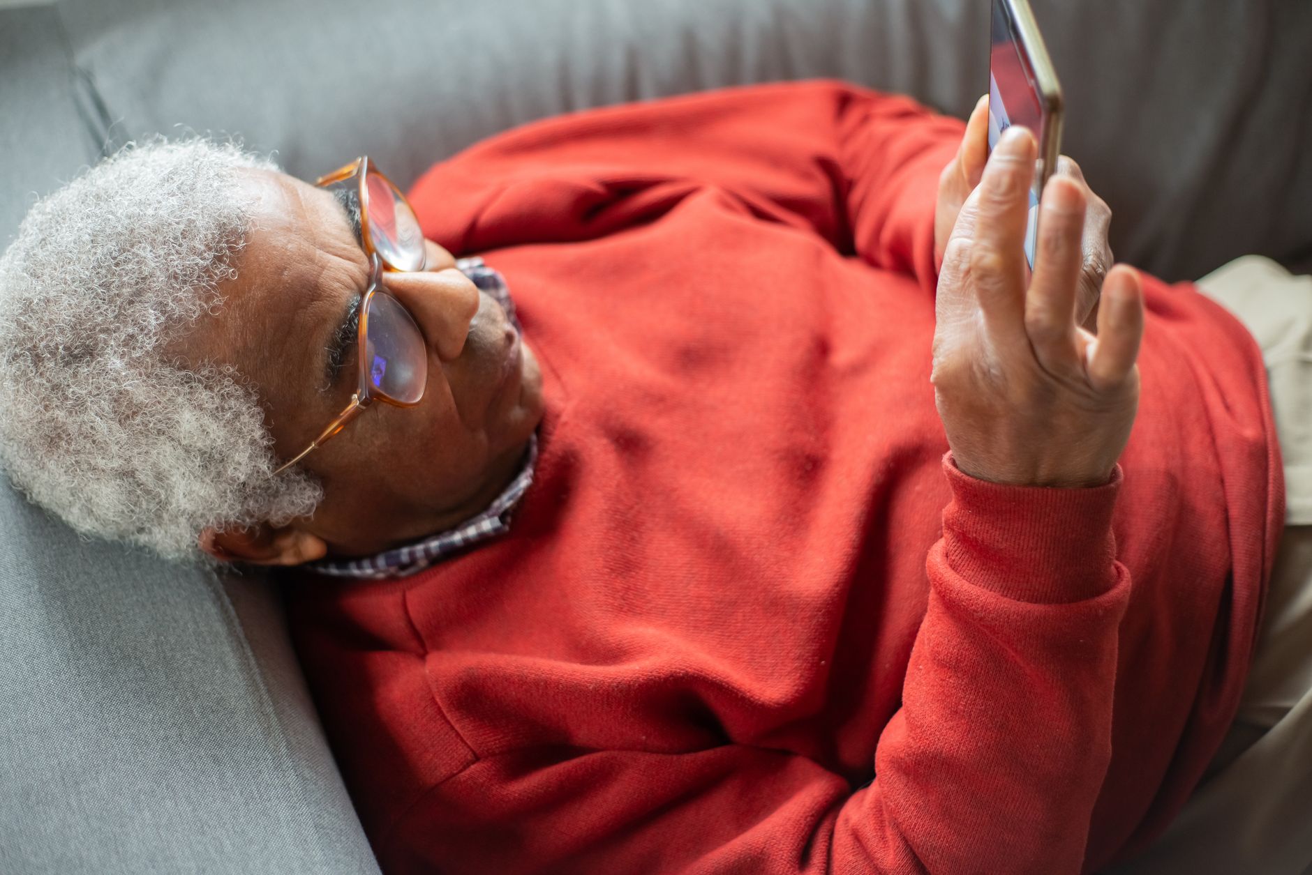 a senior sitting on a couch checking the Wi-Fi signal on a smartphone